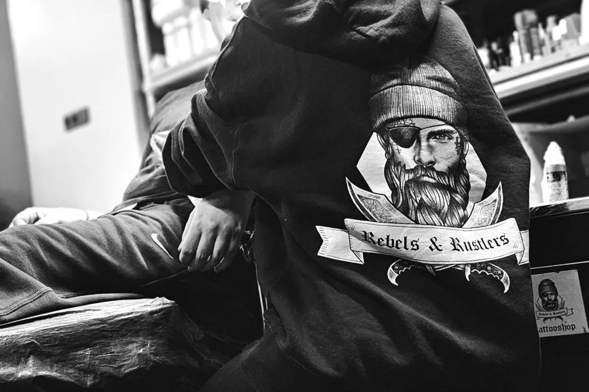 Klant in een Rebels & Rustlers hoodie in de tattoostudio